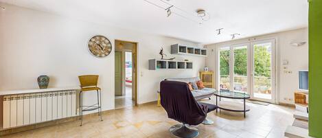 A spacious living room with a large window, a dining area, and a seating area with a chair and a table.