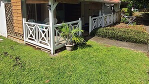 A two-story house with a covered patio and a fenced garden area. - Bungalow Style Studio vue Mer, Accès Direct Plage Véhicule de Location Possible (La Trinité)