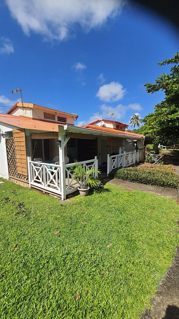 A two-story house with a covered patio and a fenced garden area.