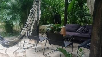 Eine Hängematte, Sitzgelegenheiten im Freien und Topfpflanzen in einem Garten.