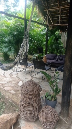 Een hangmat, buitenmeubels en planten in potten in een tuin.