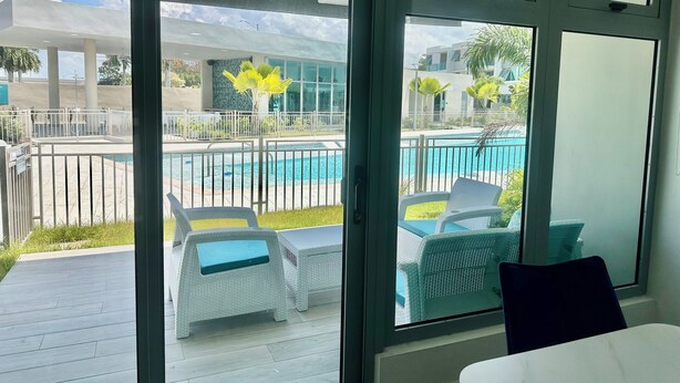 A room with a view of a swimming pool, outdoor furniture, and a balcony with a railing. - NEW 3/2 POOLFRONT. FULL BACKUP GENERATOR, 2 POOLS, NEAR BEACH, GYM, 2 PARKINGS. (Carolina)