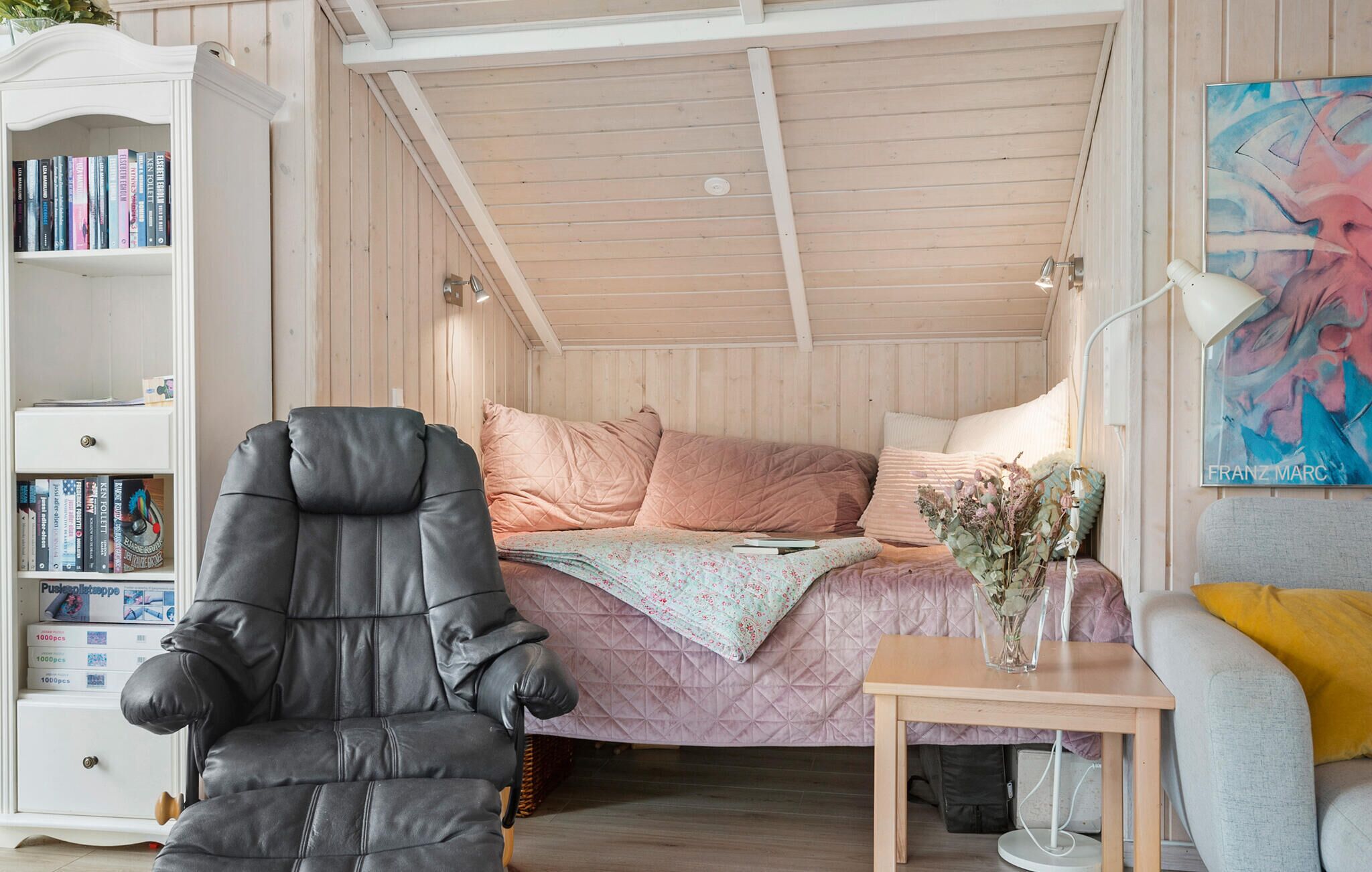 Una habitación acogedora con una cama, una estantería, un escritorio y una silla.