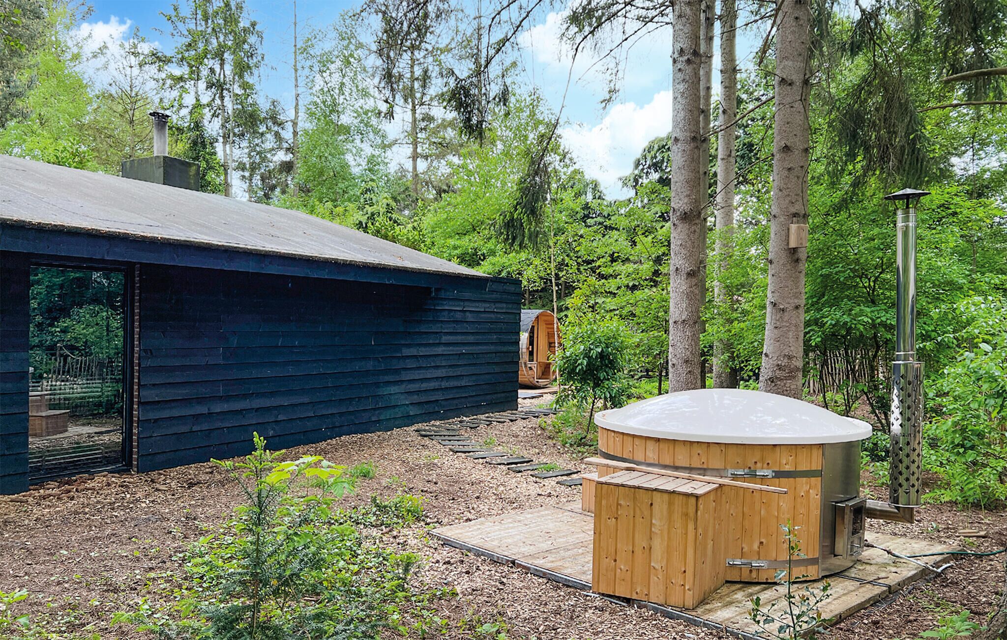 A cabin with a hot tub and a sauna, surrounded by a forest.