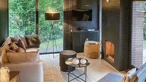 A modern living room with a sofa, a coffee table, a floor lamp, and a fireplace. - Nice home in Rheezerveen with sauna (Rheezerveen)