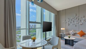 A modern hotel room with a large window, a round glass table, two armchairs, a sofa, a TV, and a decorative wall piece. - Hyatt Place Nantong Xinghu City Plaza (Nantong)