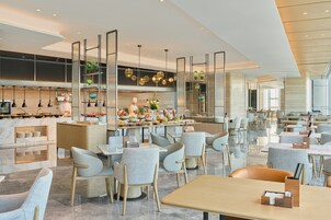 Un restaurante moderno con barra central, zona de estar y cocina al fondo.