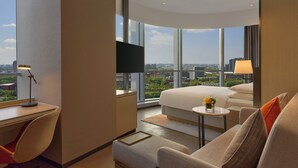 A modern hotel room with a large bed, a desk, a chair, a small table, and a TV. The room has large windows offering a city view. - Hyatt Place Nantong Xinghu City Plaza (Nantong)