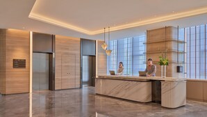 A modern reception area with a marble reception desk, a digital directory, and a large window providing natural light. - Hyatt Place Nantong Xinghu City Plaza (Nantong)