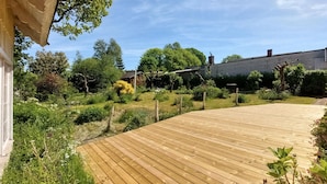 A wooden deck leading to a house with a garden and a brick building in the background. - Amazing home in Jonstorp with kitchen (Jonstorp)