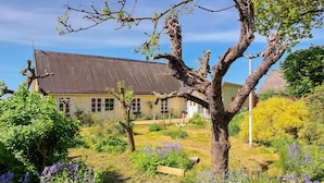A traditional house with a sloped roof, surrounded by a garden with various plants and flowers. - Amazing home in Jonstorp with kitchen (Jonstorp)