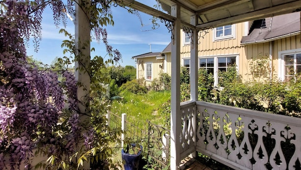 A covered porch with a white railing, a blue planter, and purple wisteria vines. - Amazing home in Jonstorp with kitchen (Jonstorp)