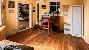A room with a wooden floor, a piano, a chair, a bookshelf, and a door. - Amazing home in Jonstorp with kitchen (Jonstorp)