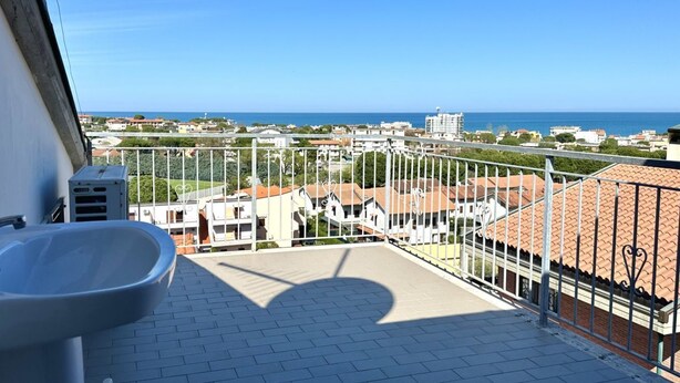 En balkon med udsigt over havet og bygninger.