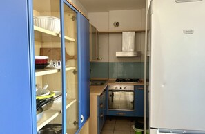 Een kleine keuken met een kookplaat, oven en blauwe keukenkastjes.