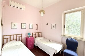 Een slaapkamer met twee bedden, een raam en wandairconditioning.
