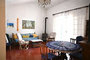 A living room with a sofa, chairs, a table, a fireplace, and a window with curtains.