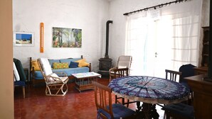 Un saló amb un sofà, cadires, una taula, una llar de foc i una finestra amb cortines.