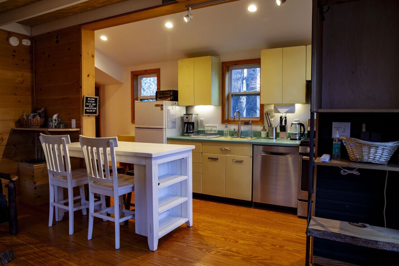 A compact kitchen with wooden cabinets, a white table, and chairs.
