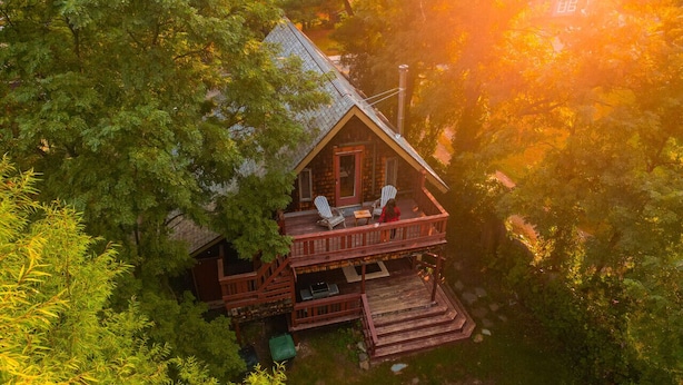 Eine Hütte mit Veranda, zwei Stühlen und einem Tisch.