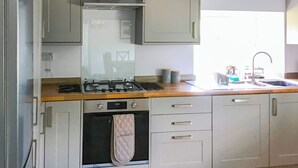 A kitchen with a stove, oven, and sink. There are cabinets above the counter and a window above the sink. - 4 bedroom accommodation in Eccles on Sea (Eccles on Sea)