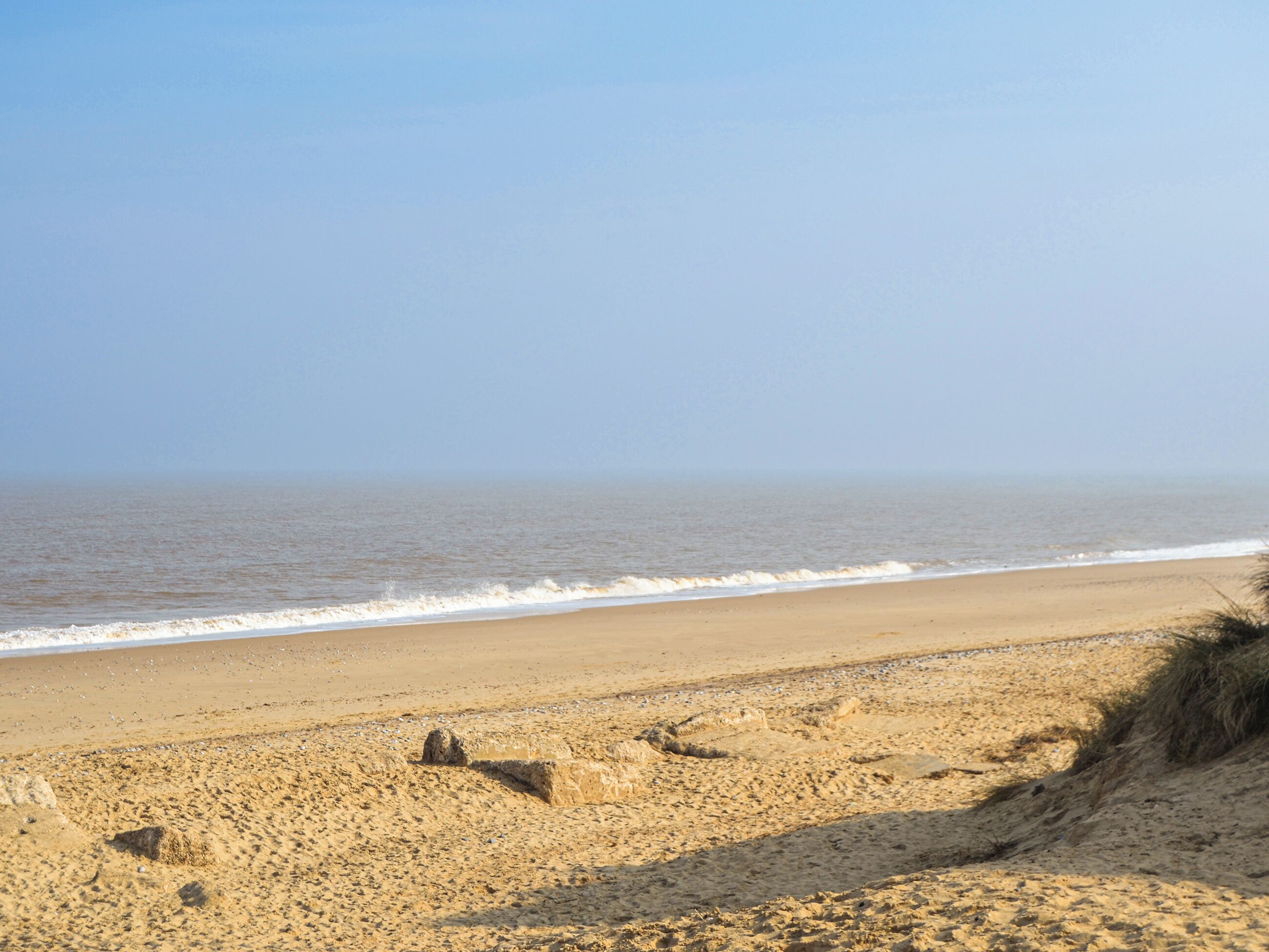 A sandy beach with gentle waves and a clear sky.