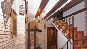 A rustic interior with a wooden staircase, a brick wall, and a stone floor. - Do you need to take a break between mountains in a charming village in Alicante? (La Torre de les Maçanes)