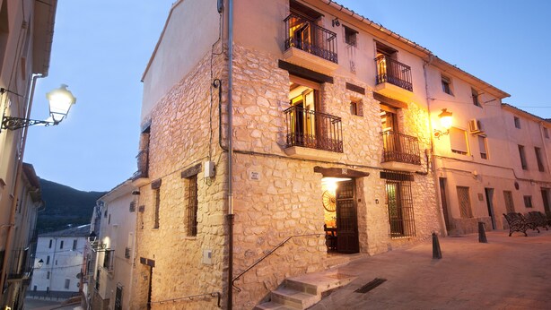 A stone building with multiple balconies, a staircase leading to the entrance, and a street lamp. - Do you need to take a break between mountains in a charming village in Alicante? (La Torre de les Maçanes)