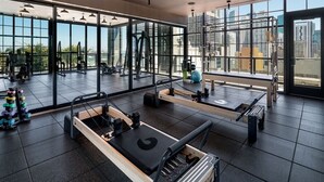 Ett modernt gym med pilatesutrustning, stora fönster och utsikt över staden.
