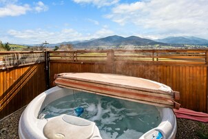 Un jacuzzi con cerca de madera y montañas al fondo.
