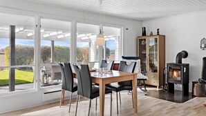 Een moderne eetruimte met een grote tafel, stoelen en uitzicht op het omliggende landschap.