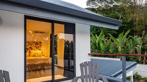 A modern house with a sliding glass door leading to a living area with a sofa and a coffee table. - Mo'a Hidden Villa (Bora-Bora)