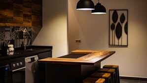 A modern kitchen with a wooden island, bar stools, pendant lighting, and a backsplash with a geometric pattern. - Mo'a Hidden Villa (Bora-Bora)