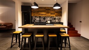 A modern kitchen with a central island, black bar stools, and pendant lighting. - Mo'a Hidden Villa (Bora-Bora)