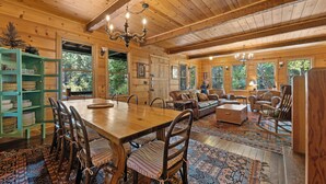 Un interior de madera con una mesa de comedor, sillas y una zona de sofás.