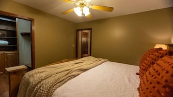 Une chambre à coucher avec un lit, un ventilateur de plafond, une armoire et une porte.