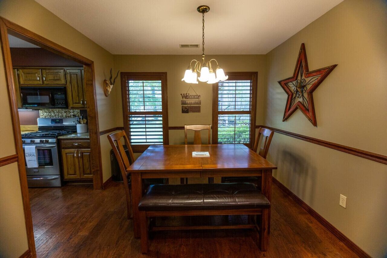 Une salle à manger avec une table en bois, des bancs et un lustre.