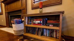 A bookshelf filled with books, a fireplace, and a cat lying on the floor.