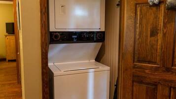 A laundry room with a washer and dryer, wooden flooring, and a sign above the door that reads "Home Sweet Home."