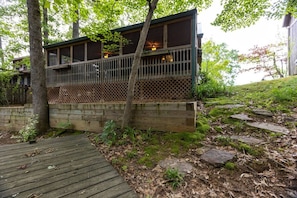 A wooden deck leading to a building with a balcony.