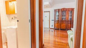 A hallway with a wooden cabinet, a white toilet, and a door leading to another room. - Residenza Edvige - Italian Homing (Verona)