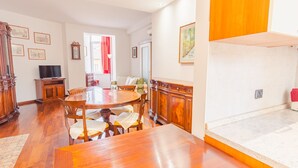 A dining area with a wooden table and chairs, a television, and a clock on the wall. - Residenza Edvige - Italian Homing (Verona)