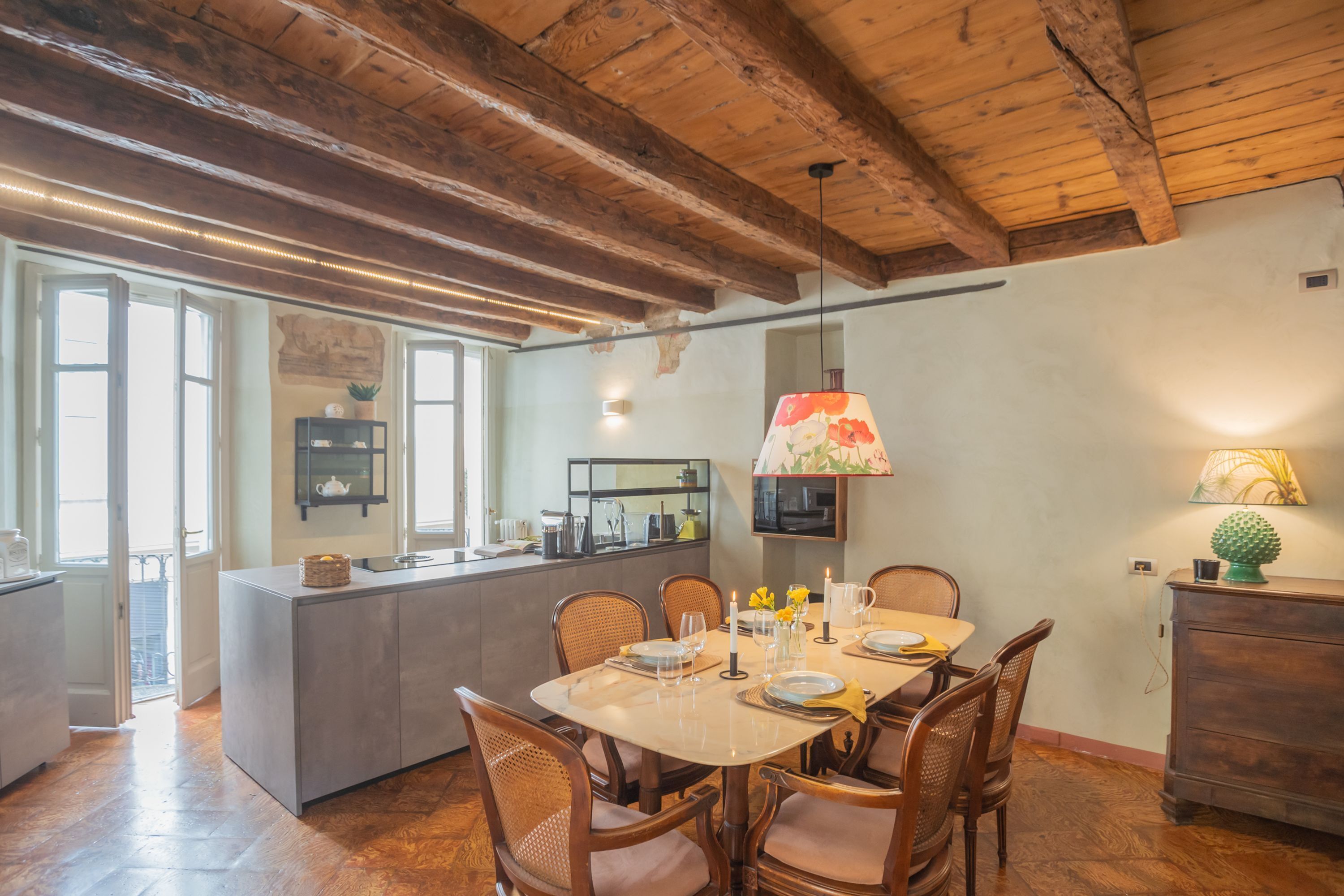 A dining area with a wooden ceiling, a central island, and a view of the kitchen.