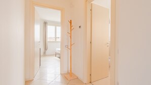 A hallway with a coat rack, a door, and a glimpse of a bedroom with a bed and curtains. - Galleria Il Principe - Italian Homing (Desenzano del Garda)