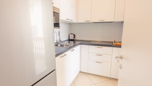 A modern kitchen with white cabinets, a black countertop, and a stainless steel sink. - Galleria Il Principe - Italian Homing (Desenzano del Garda)