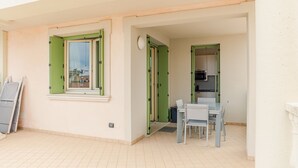 A small apartment with a dining area, a kitchen, and a window with green shutters. - Galleria Il Principe - Italian Homing (Desenzano del Garda)