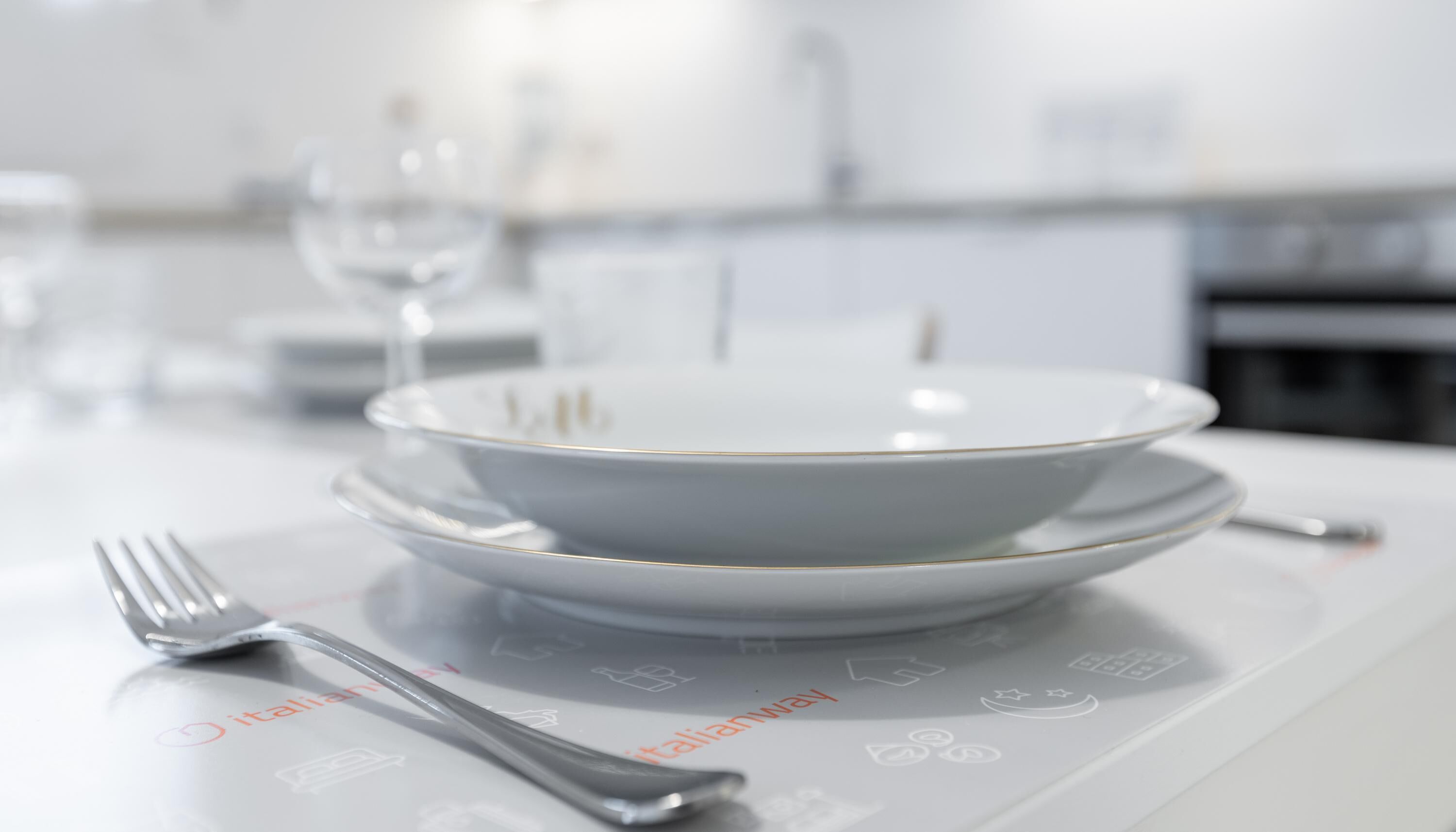 A dining table set with a white plate, a bowl, and a fork.