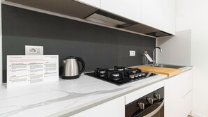 A modern kitchen with a white countertop, black stove, and stainless steel kettle. There is a recycling sign on the wall. - Italianway - Sigieri 10 (Milan)