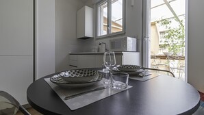 A modern kitchen with white cabinets, a microwave, and a dining area with a table set for two.