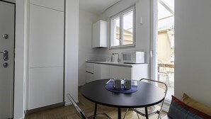 A compact kitchen with white cabinets, a microwave, and a small dining table with chairs.